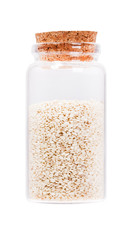Sesame seeds in a glass bottle with cork stopper, isolated on wh