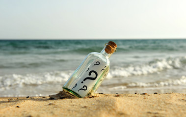 Bottle with question on the beach. Botella con preguntas en la playa