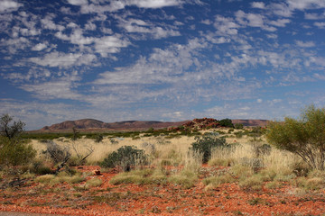 Red Rocks on Red Outback Soil with Blue Sky With Hilly Backdrop Western Australia