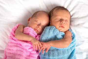 Newborn twins sleeping in cuddle together