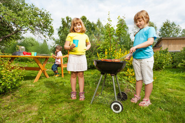 Two girls near grill making BBQ in the garden