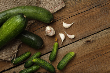 Zucchini, garlic and cucumbers on wooden background. Top view.