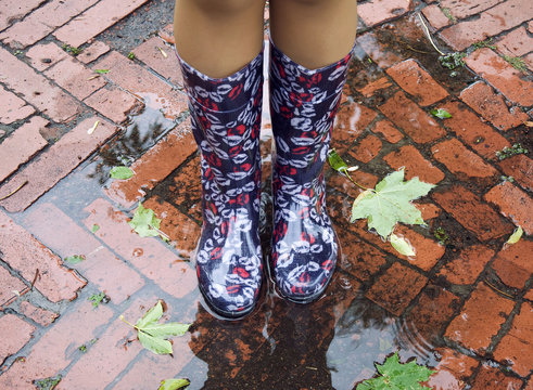 Girl Feet In Rainboots In The Puddle