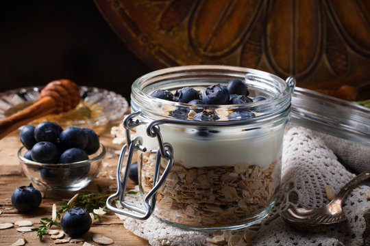 Muesli with yogurt and blue berries in glass jar.