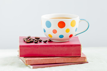 Coffee cup with roasted coffee on the books