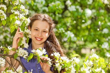 Smiling teenager girl holding white pear flowers