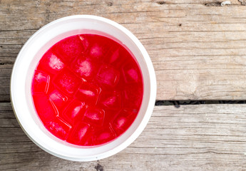 Ice in a red cocktail on wood