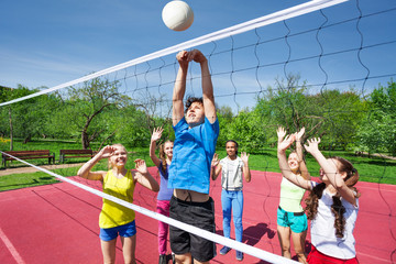 Teens all are with arms up play volleyball