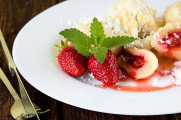 Couple of whole strawberries on white plate with dumplings