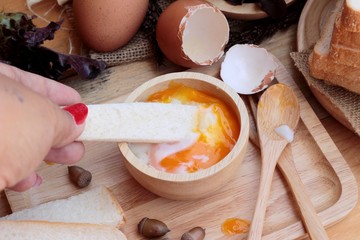 soft-boiled egg with bread on wood background.