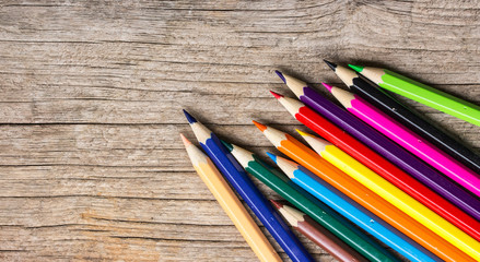 Naklejka premium Color Pencils on wooden background.