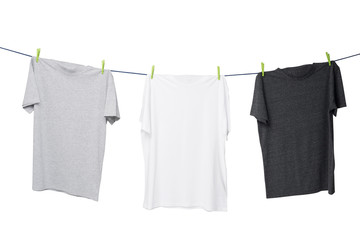 Close up of three t-shirts on the rope (grey, white and dark grey). Isolated.