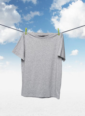 Close up of a grey t-shirts on the rope. Cloudy sky background.