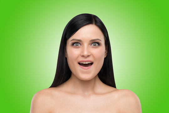 Portrait of an astonished brunette girl. Green background.