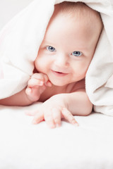 Happy baby after bathing, looks with white towels, funny smiles and looks into the camera