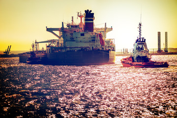 Tanker ship with tugboats on sea. Vintage toned photo.