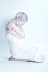 White woman sitting alone in white room