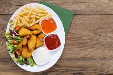 Nuggets and chips on a plate served with dip and salads