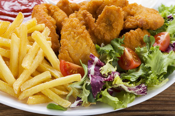 Nuggets and chips on a plate served with dip and salads