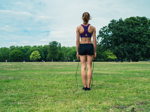 Woman in park exercising with jump rope