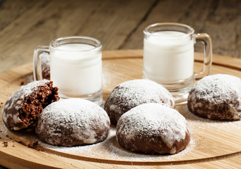 Homemade chocolate cookies sprinkled with powdered sugar and mil