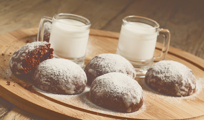 Homemade chocolate cookies sprinkled with powdered sugar and mil