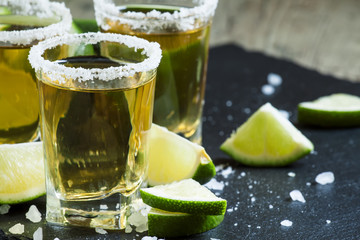 Gold Mexican tequila with lime and salt, selective focus