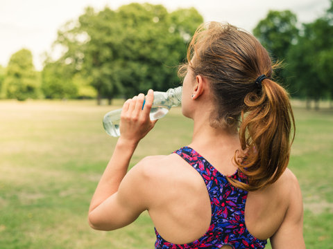 Sporty woman drinking from bottle in park