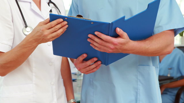 Two doctors holding clipboard in medical office