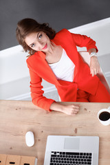 Attractive woman sitting at desk in office, working with laptop