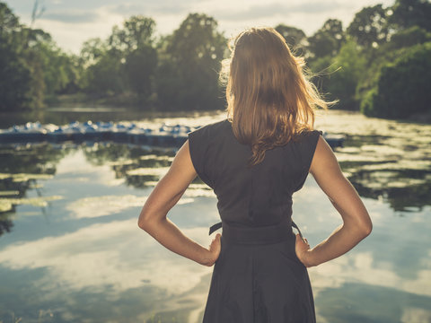 Young woman standing by lake at sunset