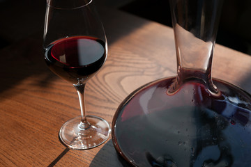 Closeup of the carafe and glass of red wine on the wooden table