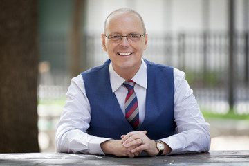 Mature Businessman Smiling At The Camera. He's working at the park