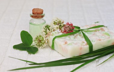 Obraz na płótnie Canvas Handmade soap bar aromatherapy oils herbal cosmetics scented clover flower fresh green leaves, relaxing bathroom care set