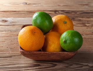 Oranges and limes in wood bowl.