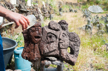 Fototapeta na wymiar Lava stone artist pouring water on the surface of a sculpture to highlight its design