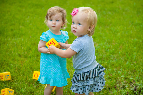 Little girls on nature playing toy
