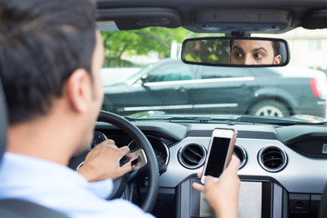 Closeup portrait, young man in blue polo shirt driving in black car and checking his phone, then...