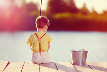 cute little boy fishing on pond at sunset © Olesia Bilkei