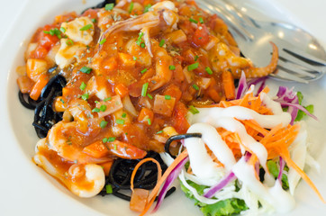 Black spaghetti with seafood on white plate