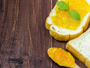 breakfast with bread and orange jam on wooden table