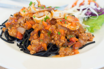 Black spaghetti with seafood on white plate