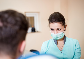 Patient at a reception at a beautiful young girl looking at her dentist
