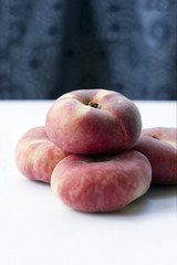Flat peaches stacked on white, with blue patterned background