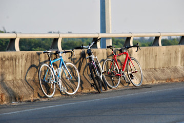 Three bicycles parked against wall by the roadside on a sunny mo