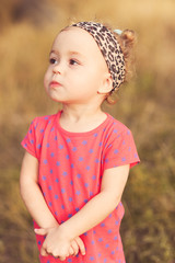 Baby girl 2-3 year old outdoors. Wearing stylish leopard pans nd headband in park. Childhood. 