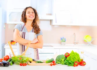 Happy young woman cooking in the kitchen at home