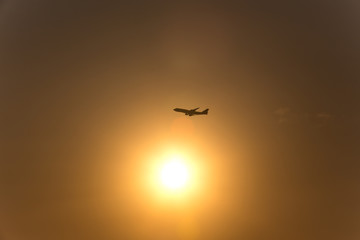 Fototapeta na wymiar airplane in front of a hot evening sun