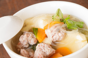 clear soup with pork in white plate put on wooden background, Thai cuisine.