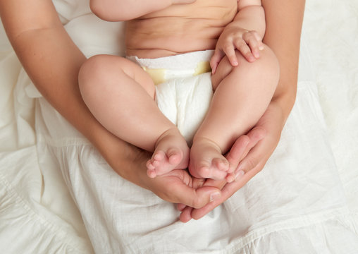baby legs in mother hands on white